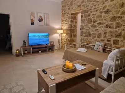 a living room with a couch and a television at Stone Apartment Close to the Airport in Spáta