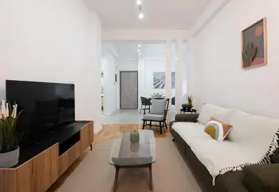 a living room with a couch and a tv at LIV - Comfortable & Stylish Escape in Pagrati in Athens
