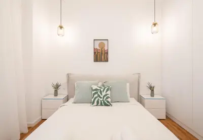 a white bedroom with a bed with two night stands at LIV - Comfortable & Stylish Escape in Pagrati in Athens