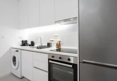 a kitchen with white cabinets and a stainless steel refrigerator at LIV - Comfortable & Stylish Escape in Pagrati in Athens