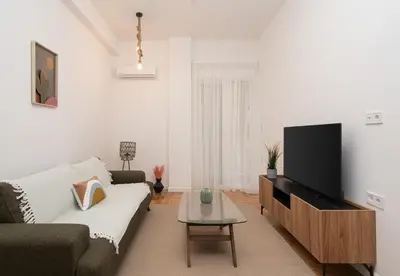 a living room with a couch and a flat screen tv at LIV - Comfortable & Stylish Escape in Pagrati in Athens
