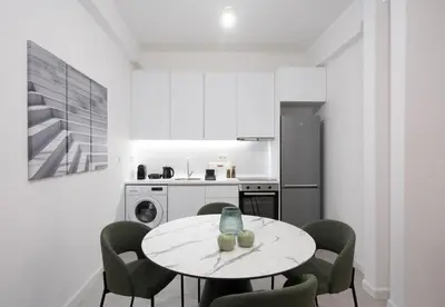 a white kitchen with a table and chairs at LIV - Comfortable & Stylish Escape in Pagrati in Athens