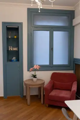 a living room with a red chair and a window at 1900's Athens Residence in Athens