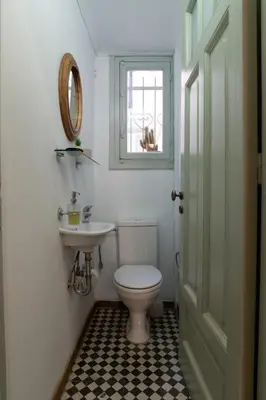 a bathroom with a toilet and a sink and a window at 1900's Athens Residence in Athens