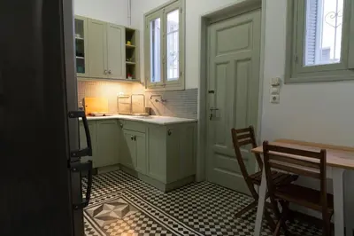 a kitchen with green cabinets and a table and chairs at 1900's Athens Residence in Athens
