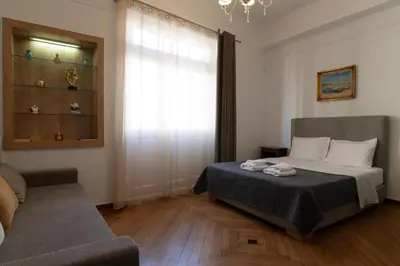 a bedroom with a bed and a couch and a window at 1900's Athens Residence in Athens