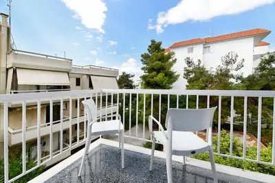 a pair of white chairs sitting on a balcony at Zana's cozy Apartment at Glifada in Athens