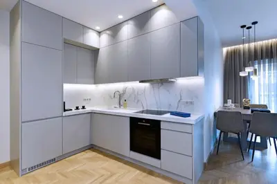 a kitchen with white cabinets and a table with chairs at Zana's cozy Apartment at Glifada in Athens