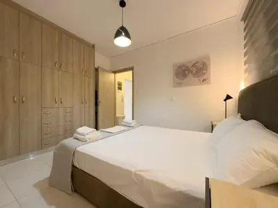 a bedroom with a large white bed and wooden cabinets at NAGIA Modern Apt Paleo Faliro B-1 in Athens
