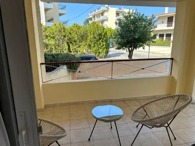 a balcony with two chairs and a window at Mesogaia Home Near ATH Airport in Markopoulo