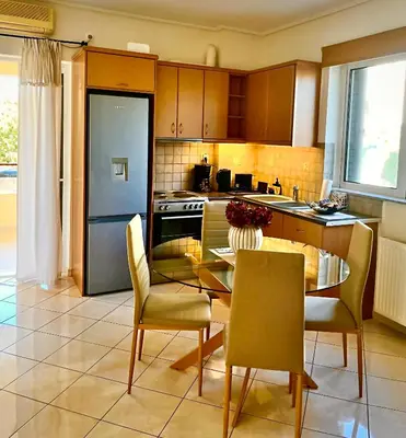 a kitchen with a table and chairs and a refrigerator at Mesogaia Home Near ATH Airport in Markopoulo