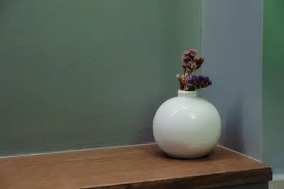a white vase with flowers in it sitting on a table at Livelula apartment in Athens