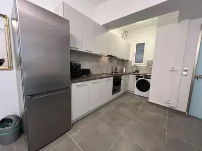 a kitchen with white cabinets and a stainless steel refrigerator at Piano Quiet Apartment Garden in Athens