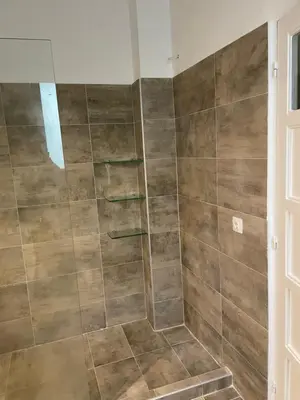 a bathroom with a shower with brown tiles at Quiet just renewed apartment in Neapolis in Athens