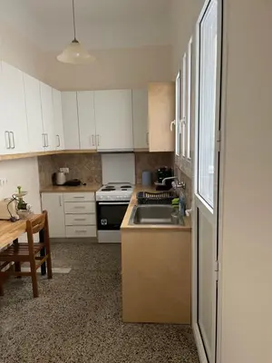 a kitchen with white cabinets and a sink and a table at Quiet just renewed apartment in Neapolis in Athens