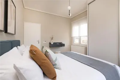a bedroom with a bed with white sheets and pillows at Beaming 2BR Apartment in Paleo Faliro by UPSTREET in Athens