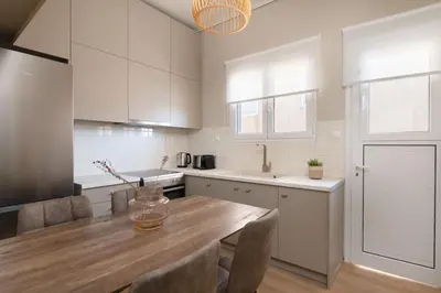 a kitchen with white cabinets and a wooden table at Beaming 2BR Apartment in Paleo Faliro by UPSTREET in Athens