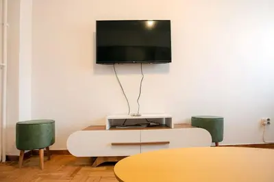 a living room with a table and a tv on a wall at Stylish And Comfortable Apartment in Athens