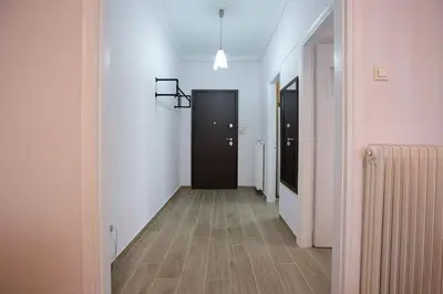 a hallway with two black doors and a wooden floor at Stylish And Comfortable Apartment in Athens