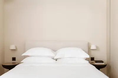 a white bed with two pillows and two tables at Likno Athens in Athens