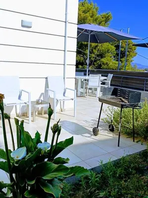 a patio with a grill and an umbrella and chairs at Porto SkyLine in Porto Rafti