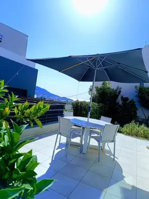 a table and chairs with an umbrella on a patio at Porto SkyLine in Porto Rafti