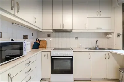 a kitchen with white cabinets and a stove and a sink at Beach of Falio in Athens