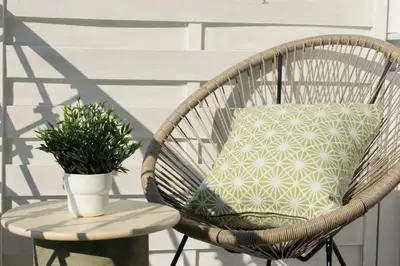 a wicker rocking chair with a pillow and a potted plant at Gargaretta Suites Wildflower 3 Acropolis Museum District in Athens