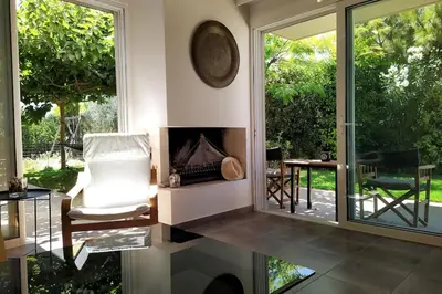 a living room with a chair and a fireplace at Garden house by the sea in Vari