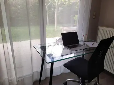 a glass desk with a laptop on it in front of a window at Garden house by the sea in Vari