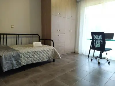 a bedroom with a bed and a desk and a chair at Garden house by the sea in Vari