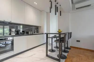 a kitchen with white cabinets and a black counter at Voula's 2BR Escape Elegant and Stylish Living in Athens