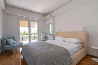 a bedroom with a bed and a chair and a window at Voula's 2BR Escape Elegant and Stylish Living in Athens