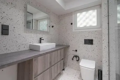 a bathroom with a sink and a toilet and a mirror at Voula's 2BR Escape Elegant and Stylish Living in Athens