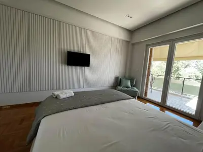 a bedroom with a bed and a tv on the wall at Voula's 2BR Escape Elegant and Stylish Living in Athens