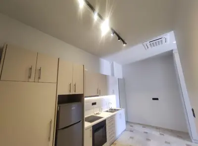 a kitchen with white cabinets and a black refrigerator at Astak in Piraeus