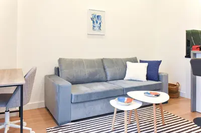 a living room with a blue couch and two tables at Cozy apartment in Pireus in Piraeus