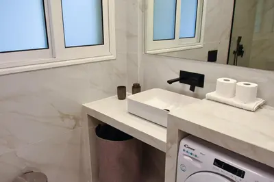a bathroom with a sink and a washing machine at Cozy apartment in Pireus in Piraeus