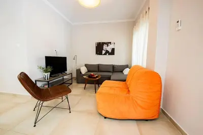 a living room with an orange chair and a couch at 'Home Downtown' in Athens