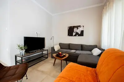a living room with a couch and a flat screen tv at 'Home Downtown' in Athens