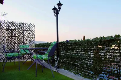 a table and chairs next to a fence with a hedge at Athens studio with a view in Athens
