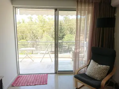 a living room with a chair and a sliding glass door at Athens Riviera Beach Retreat in Athens