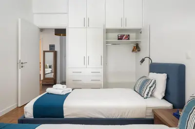 a bedroom with a bed and a blue chair at Glimmer 2-Bedroom Apartment in Athens in Athens