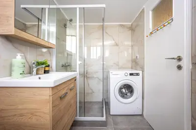 a bathroom with a washing machine and a shower at Upper House in Athens
