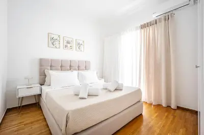 a white bedroom with a large bed with white pillows at Upper House in Athens