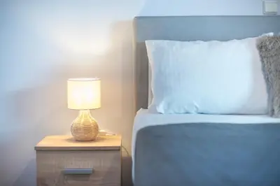 a bed with a night stand with a lamp on it at Shoreline Athens Riviera in Athens