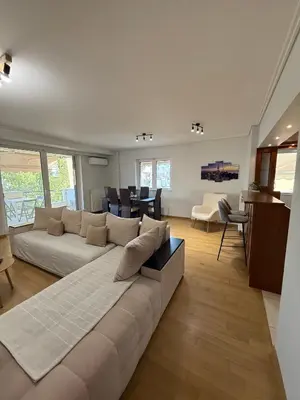 a living room with a large couch and a kitchen at Elliniko Luxury Apartment in Athens