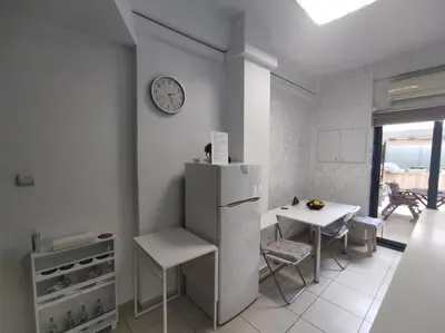 a kitchen with a refrigerator and a table and a clock at Angel's Yard in Athens Heart in Athens