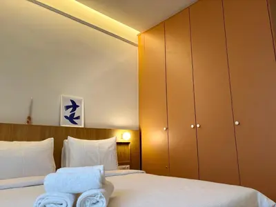 a bedroom with a bed with white sheets and brown cabinets at Aegis Filoppapou suites - Olive in Athens