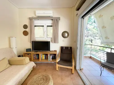 a living room with a couch and a tv at Saronida Beach Nest Apartment in Saronida